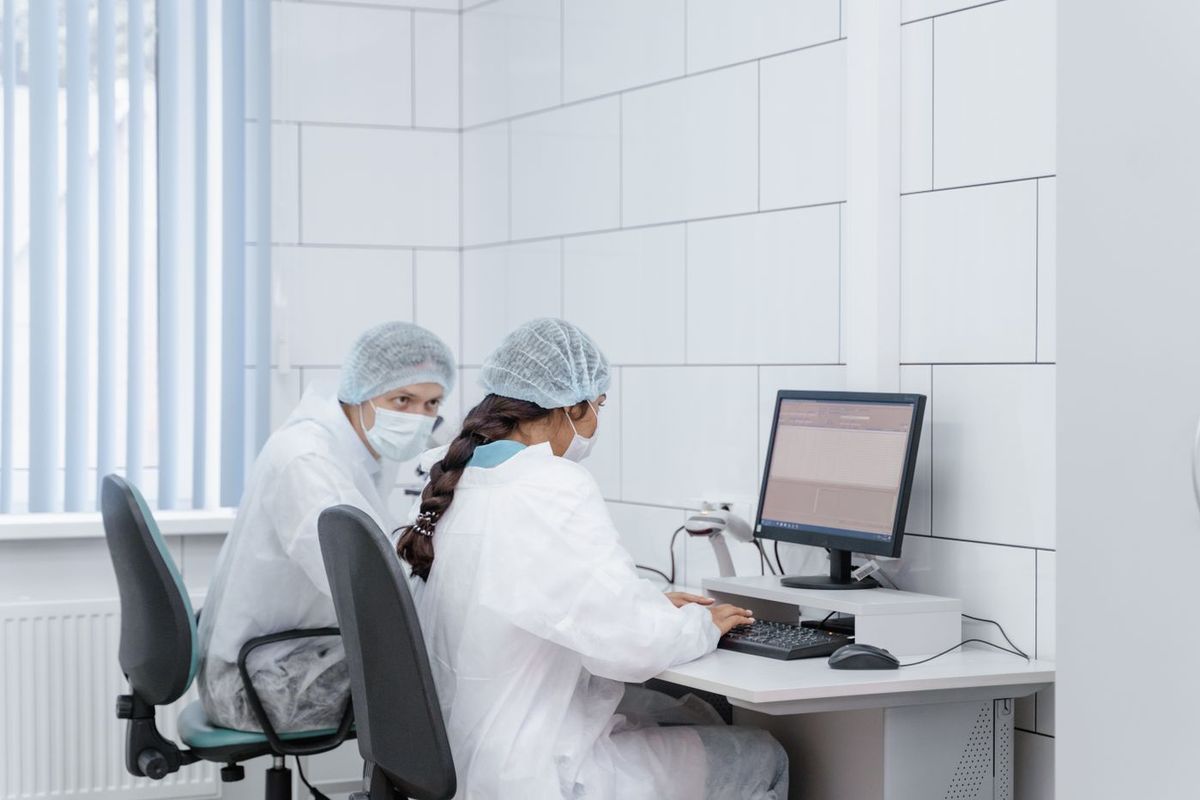 Lab technologists working at an LIS workstation in a clinical laboratory while planning how to switch LIS systems