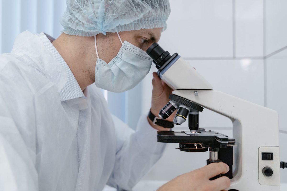 Laboratory scientist examining a slide under a microscope in a high-complexity clinical laboratory